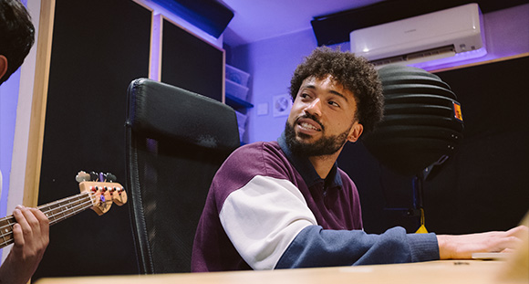 a young artist sitting at the desk of the recording studio at Root Seventy Three