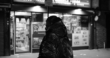 a woman walking on a dark street with a convenience store